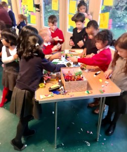 A group of children standing around a craft table and participating in Designing My Happy City: Playground.