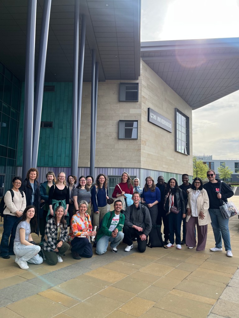 A group of people posed outside in front of a contemporary looking building