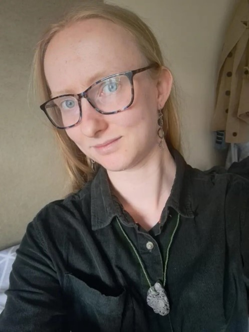 A headshot of a woman with straight blond hair and square, tortoiseshell glasses.