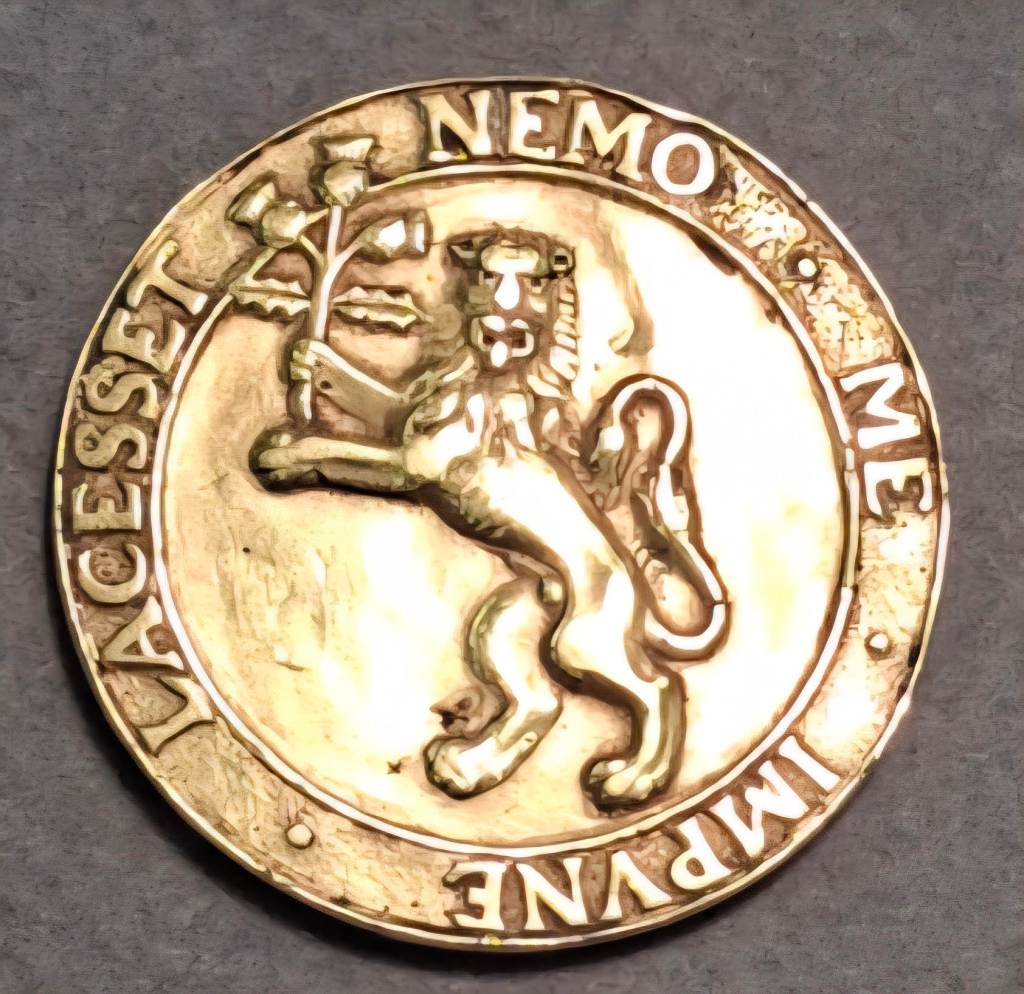 A zoomed in image of a gold coin. A lion holds a bouquet of flowers. Latin words are engraved on the rim of the coin.