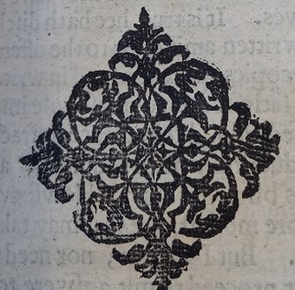A zoomed in image of a print from the page of a book. It is a detailed symbol printed in black ink, looking like a crest of some sort.
