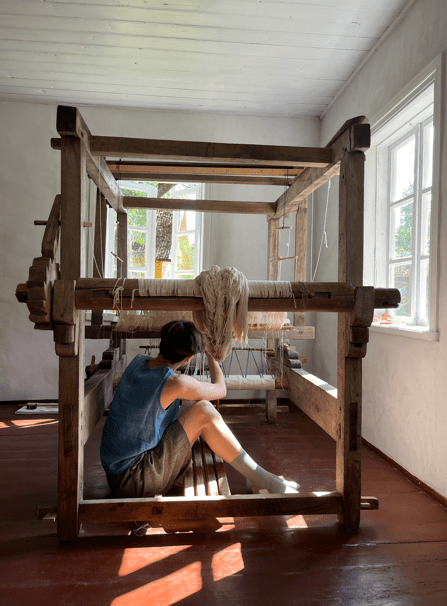 Cecilia in and under the loom. Credit Cecilia Charlton.
