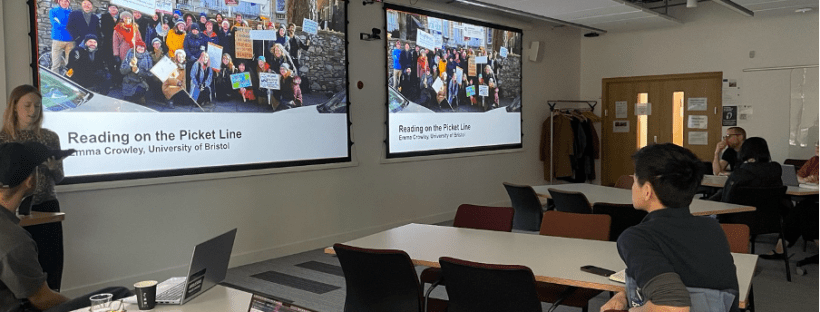 Keynote session at the University of Glasgow with attendees seated in a seminar room while a presentation slide titled “Reading on the Picket Line” is displayed.