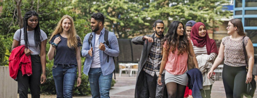 A diverse group of university students walking together across a campus.