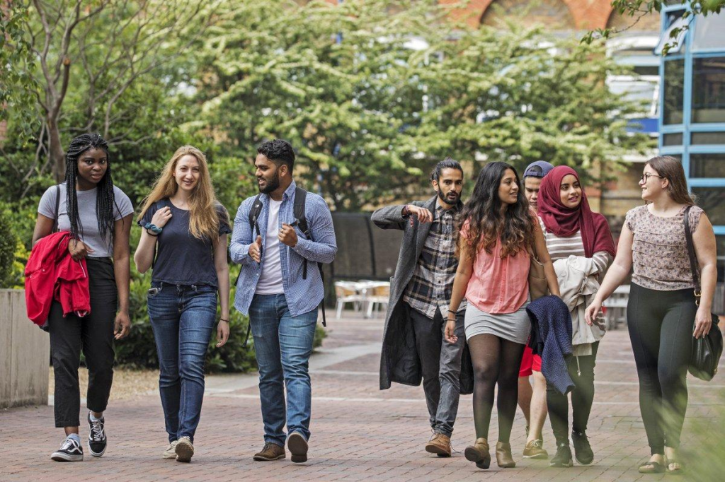 A diverse group of university students walking together across a campus.