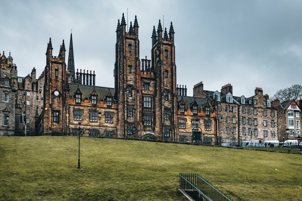 The Gothic stone façade of New College, University of Edinburgh's School of Divinity, with its imposing towers overlooking The Mound in Edinburgh.